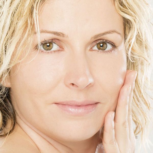 Smiling blond woman holding hand to face
