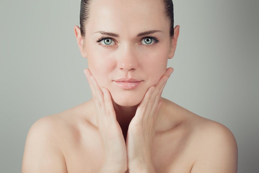 Beautiful woman with blue eyes holding hands to cheeks