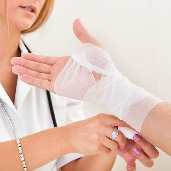 Female medical practitioner wrapping hand in gauze
