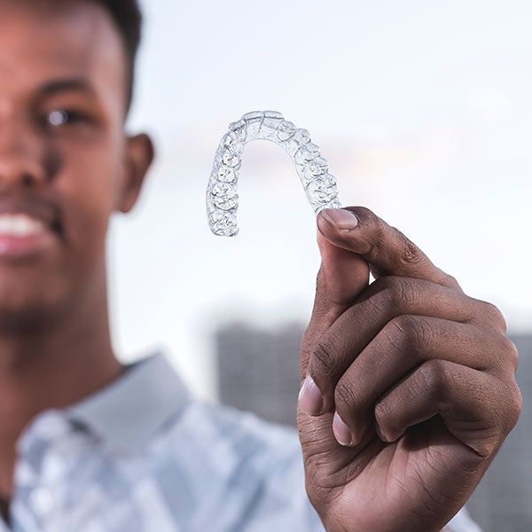 man holding up clear aligner