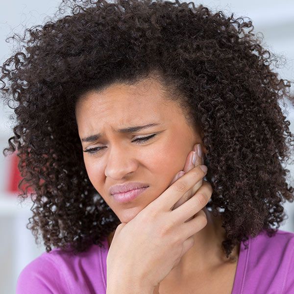 woman holding her face in pain