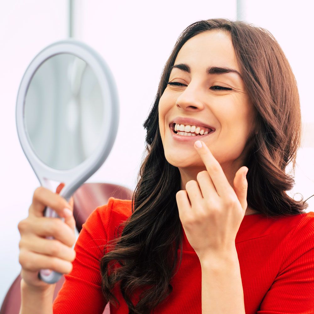 Woman examining smile in mirror