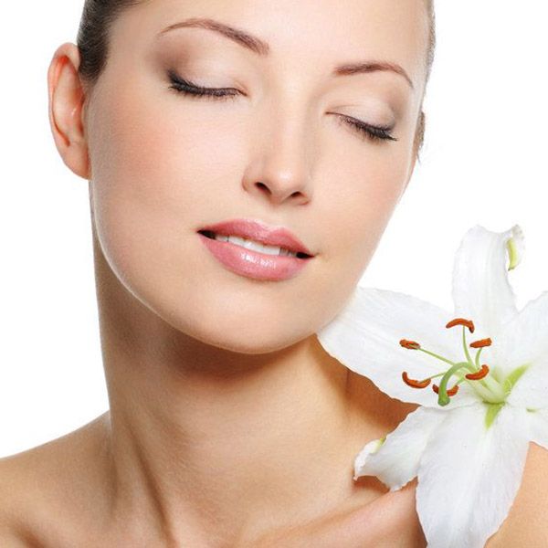 A woman with her eyes closed holding a white lily