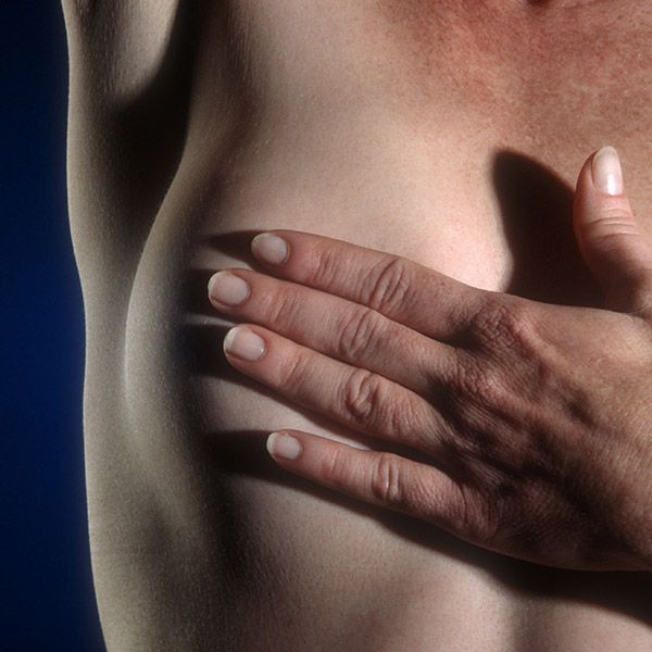 Woman holding hand over bare breast