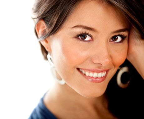 A smiling young woman touching her long brunette hair.