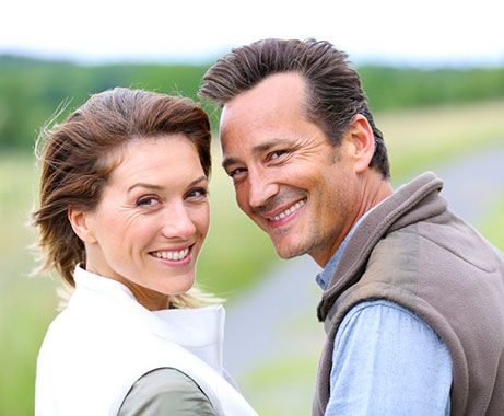 A couple outdoors smiling over their shoulder.