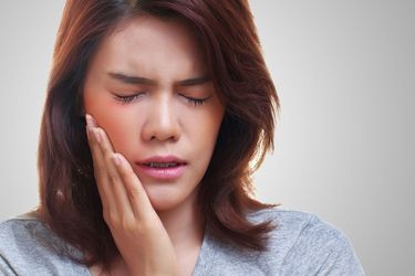 Photo of woman holding jaw in pain