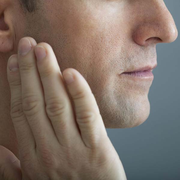 A man with a hand to his cheek