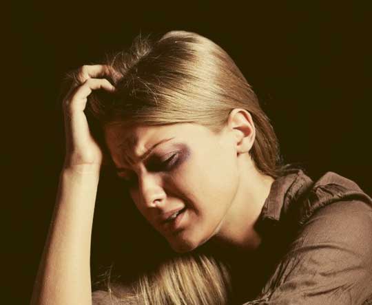A blonde woman looking distraught in a dark room