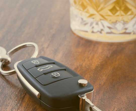A car key lying beside a glass of liquor