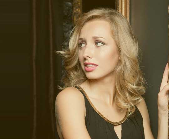 A blonde woman in a dress looking over her shoulder