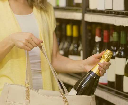 A woman putting a champagne bottle into her purse