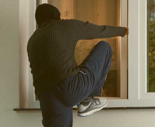 A burglar entering a home through a window