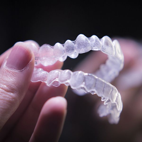A person holding two Invisalign aligners
