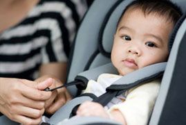 Infant being buckled into a car seat