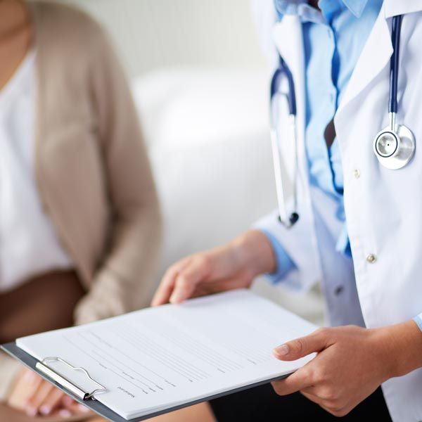 Doctor holding a clipboard while speaking with a patient