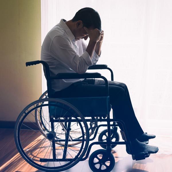 Man in wheelchair with head in hands