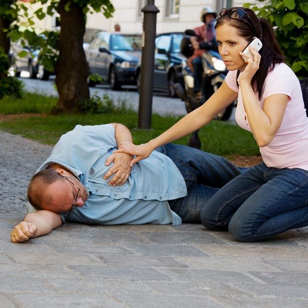 Woman on phone helping man who fell on sidewalk