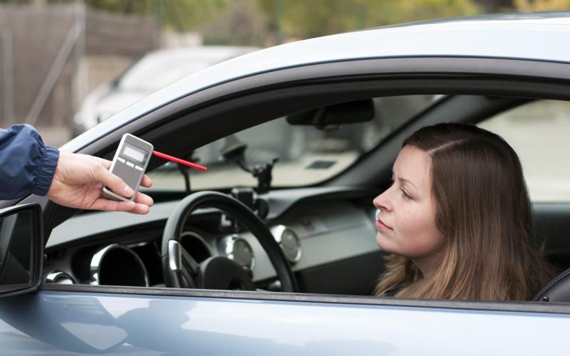 Photo of a woman in car taking breathalyzer test