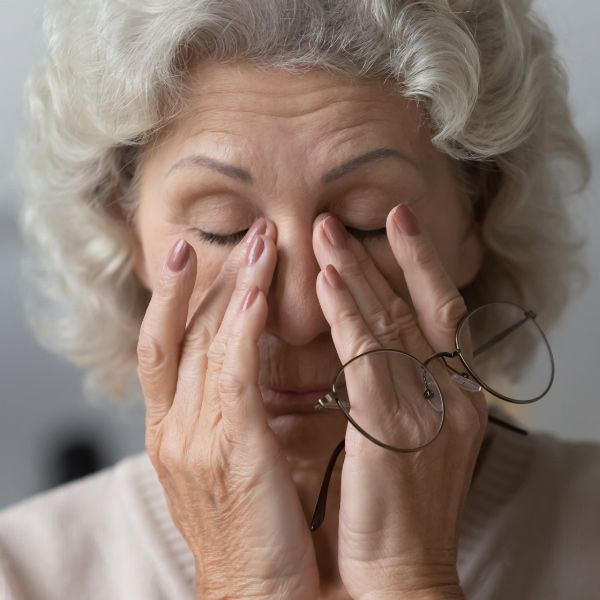 An older woman rubbing her eyes