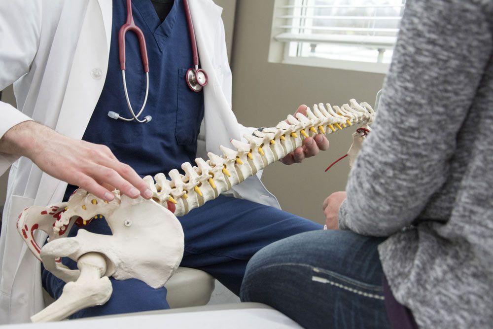 A chiropractor discussing chiropractic care using a spinal prop.