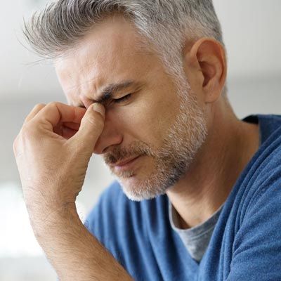 Man holding brow because of a chronic migraine headache