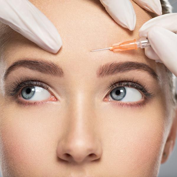 Close up of a woman receiving an injection in her forehead