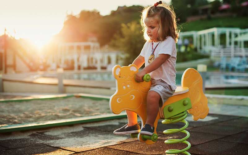 Young girl riding rocking horse on playground