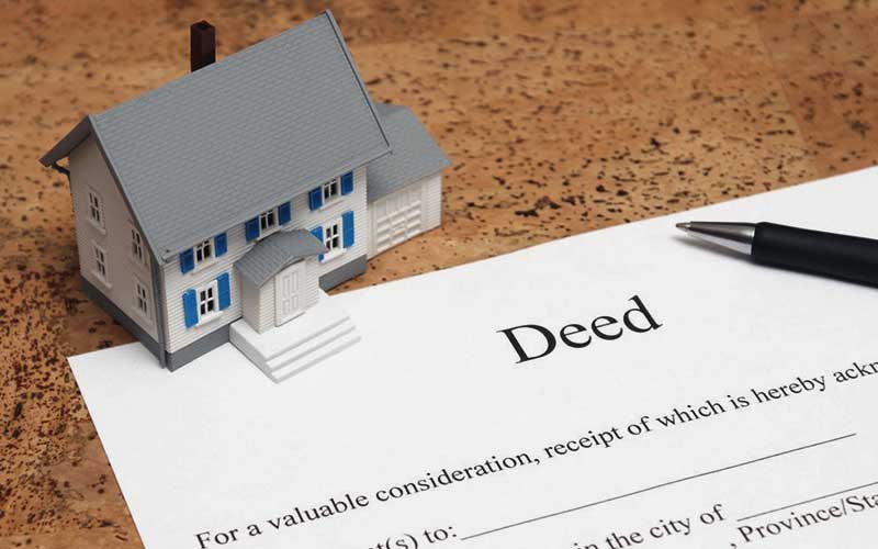 Toy house on top of deed paperwork