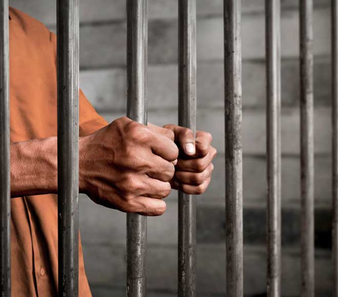 Man clutching jail cell bars