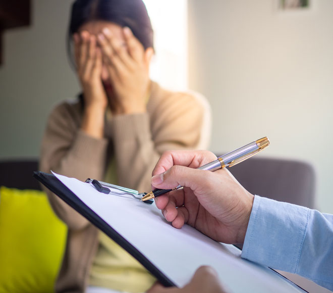 Woman holding hands over face while man completes paperwork