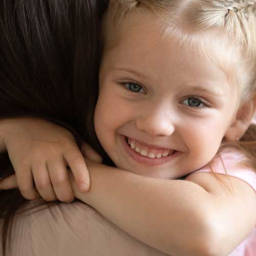 Smiling girl being hugged by woman