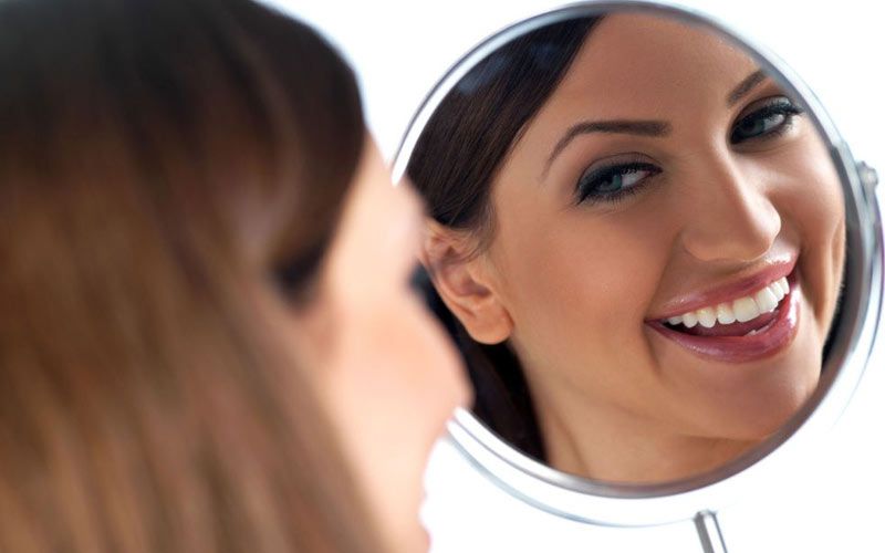 woman smiling into mirror