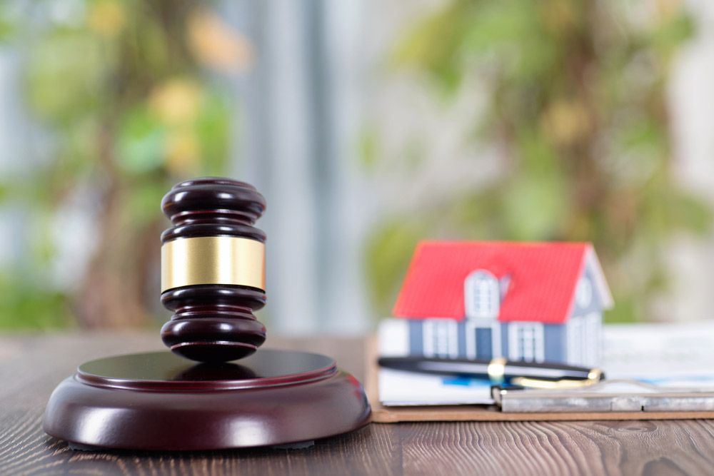 A gavel, pen, and tiny house on a desk.