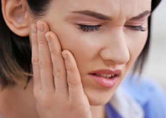 Woman holding hand to jaw in pain