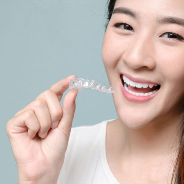 a woman holding clear aligners