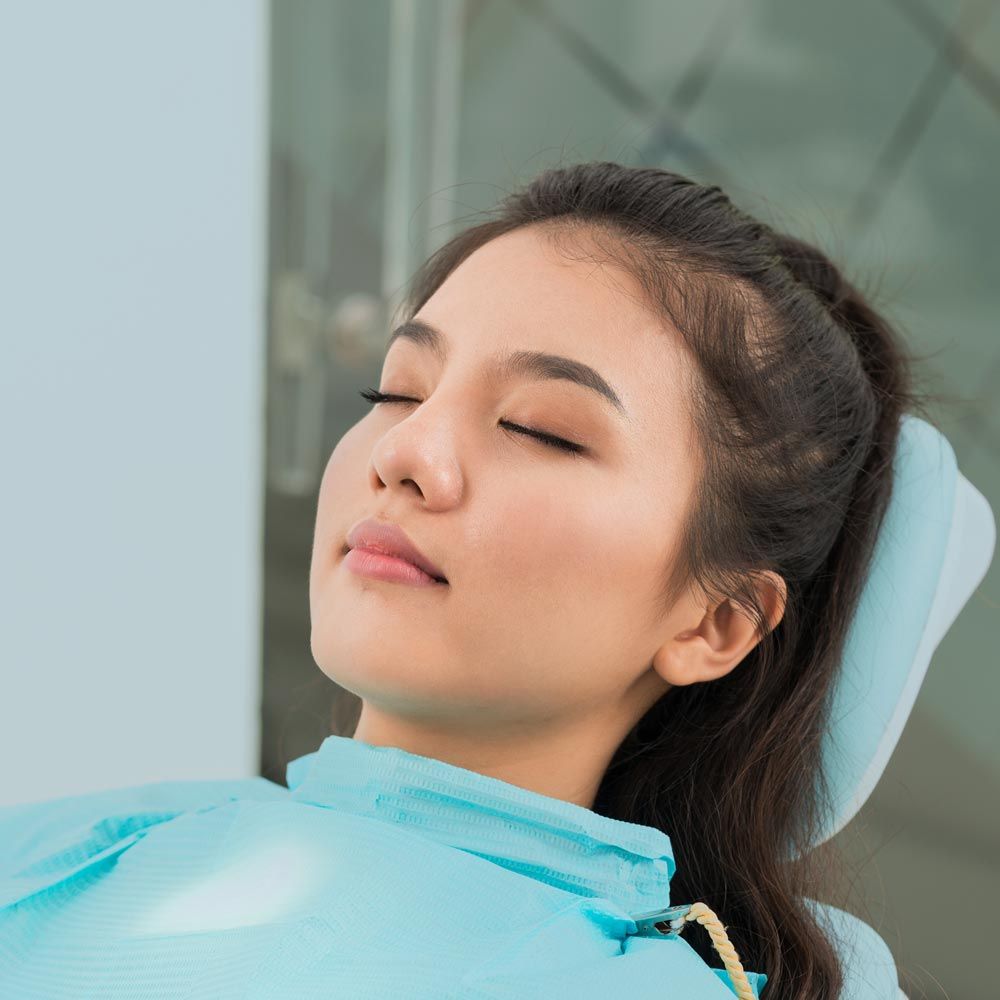 Woman lying in dentist's chair with eyes closed